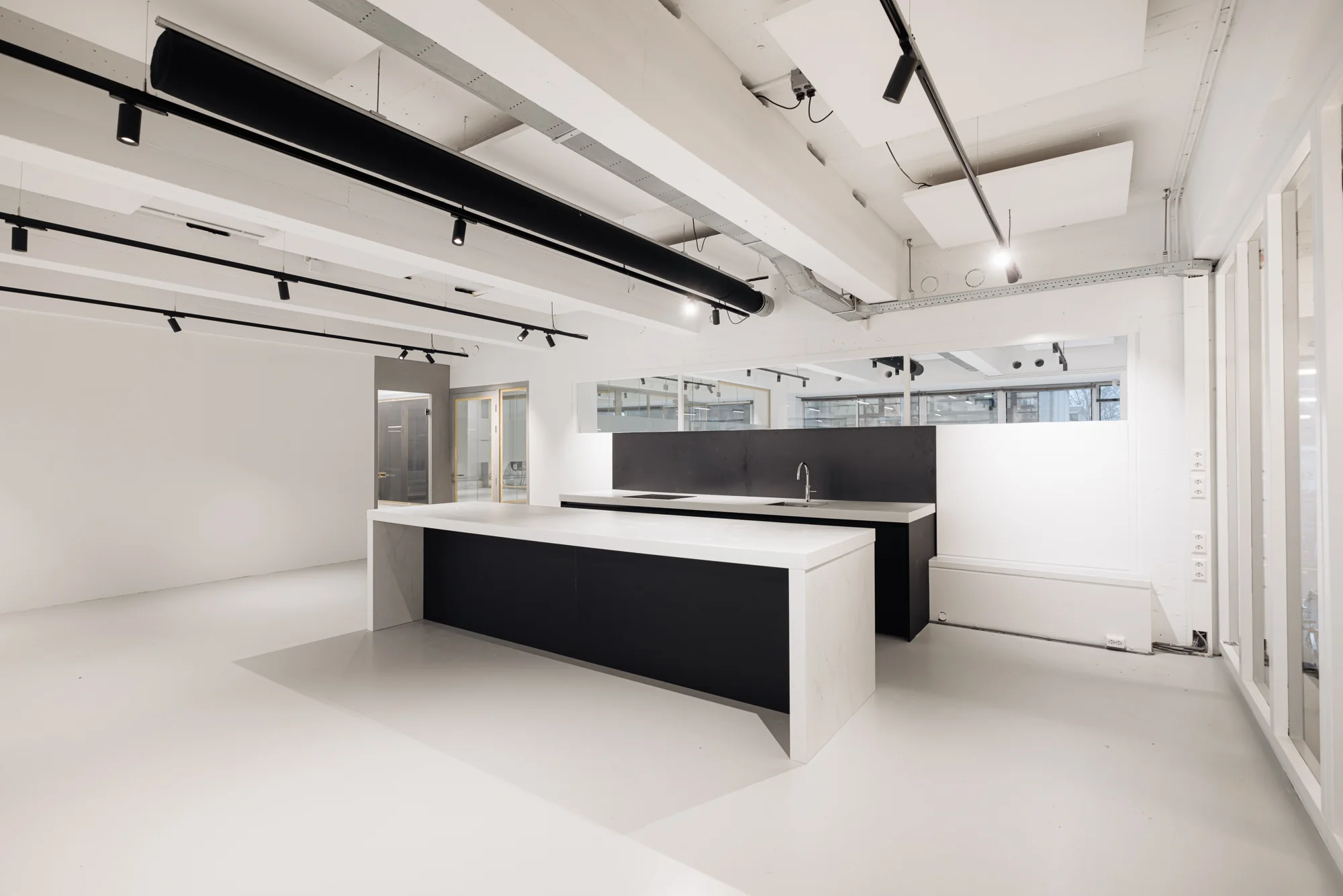 Moderne, minimalistische keuken met zwart-wit kookeiland in een strak afgewerkte ruimte aan de Generaal Vetterstraat.