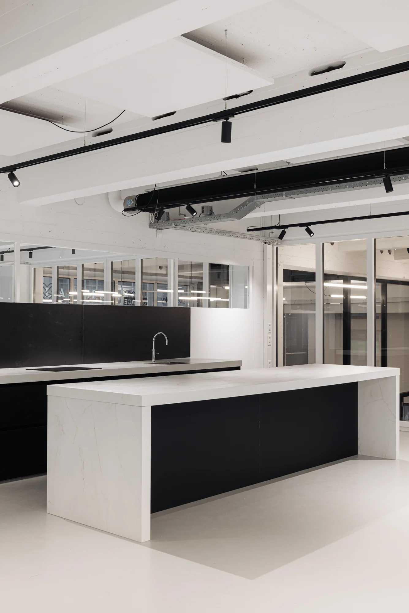 Moderne zwarte en witte keuken met kookeiland in een strak ingericht interieur aan de Generaal Vetterstraat.