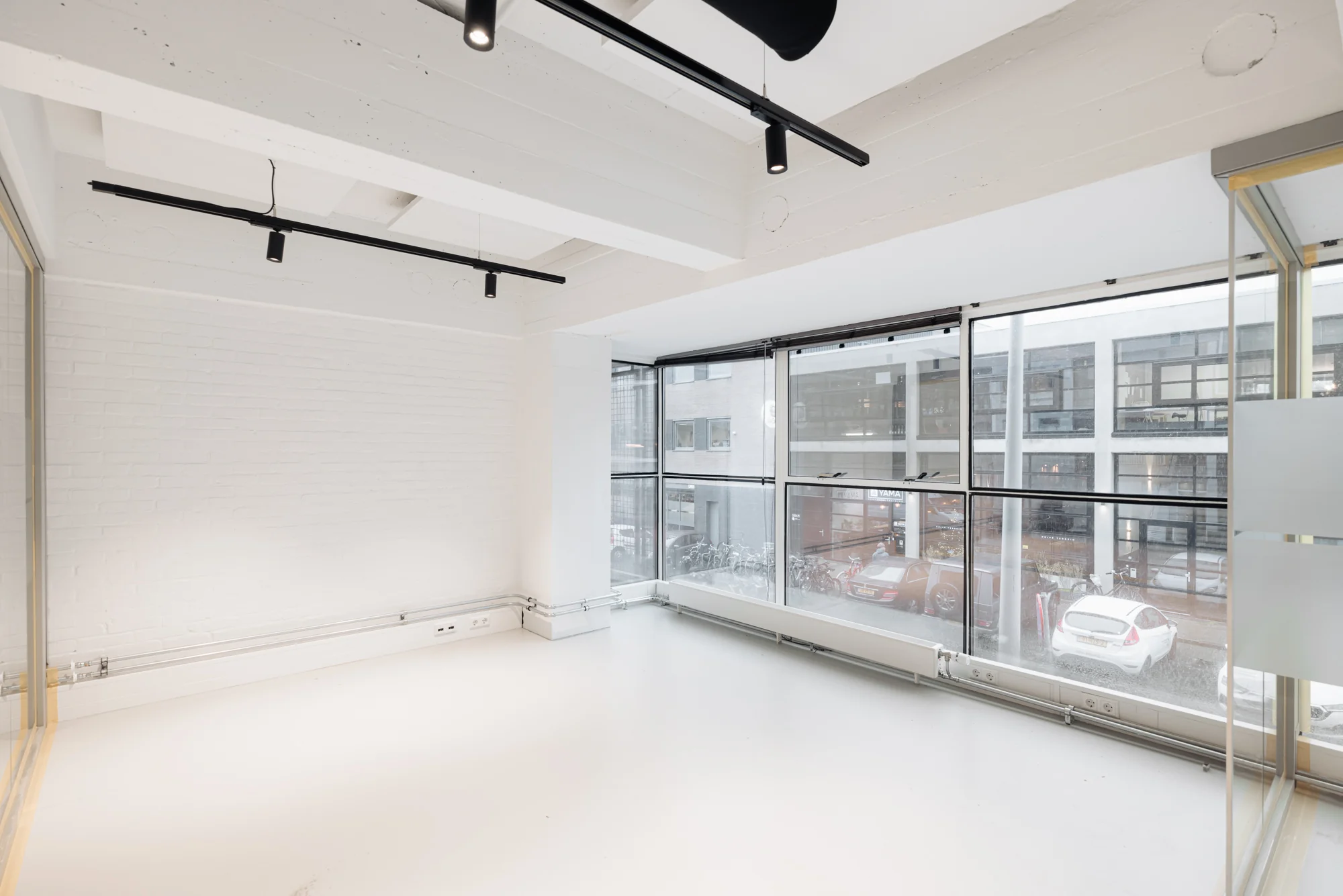 Lichte, lege kantoorruimte aan de Generaal Vetterstraat met grote ramen en uitzicht op een stadsstraat.