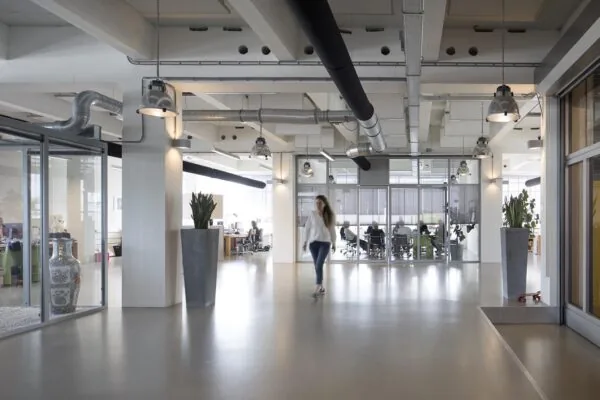 Moderne kantoorruimte aan de Generaal Vetterstraat met glazen wanden, industriële plafonddetails en mensen aan het werk.