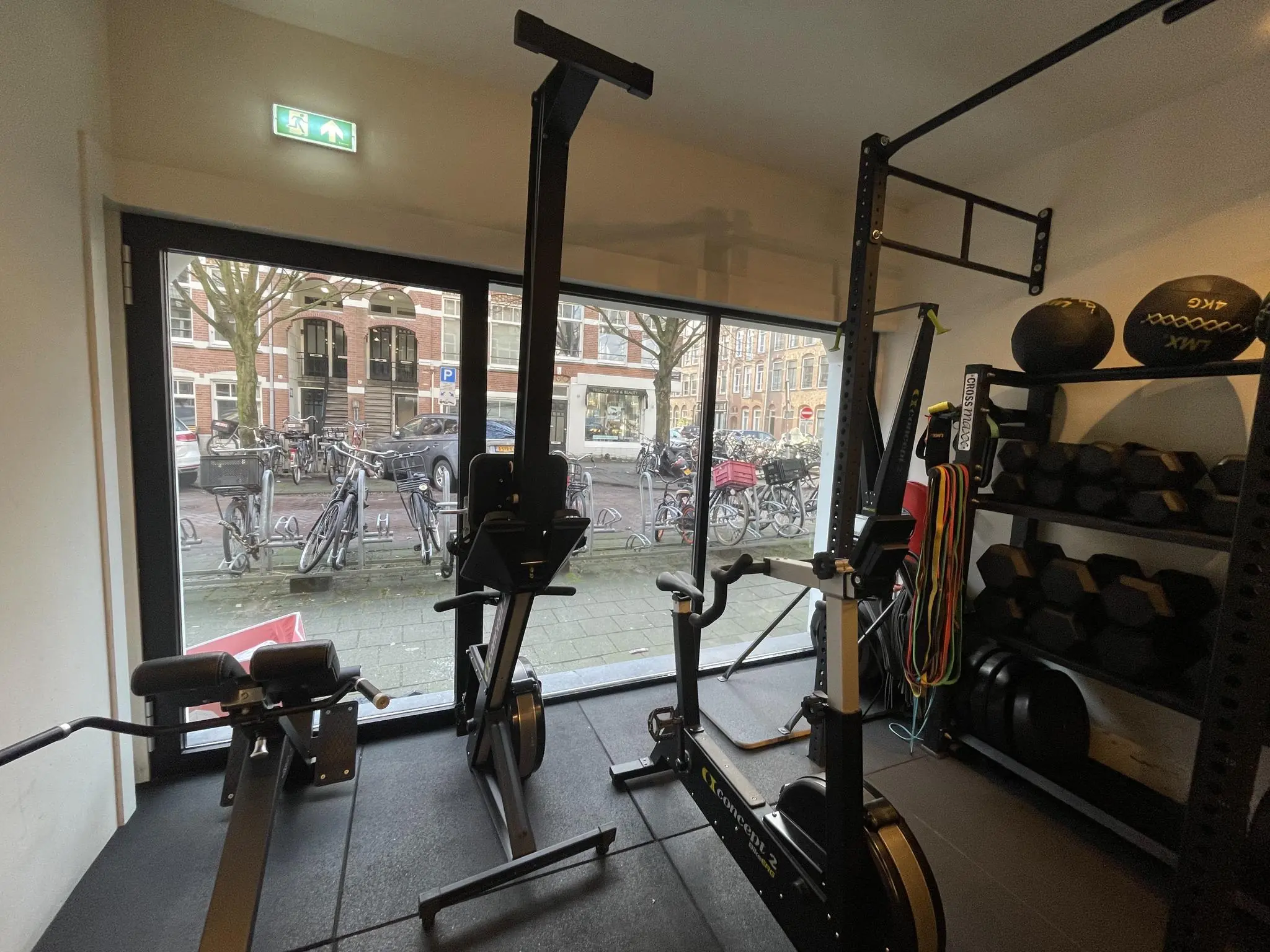 Fitnessruimte aan de Pieter Baststraat met fitnessapparatuur, halterschijven en een rek met weerstandsbanden en medicijnballen.