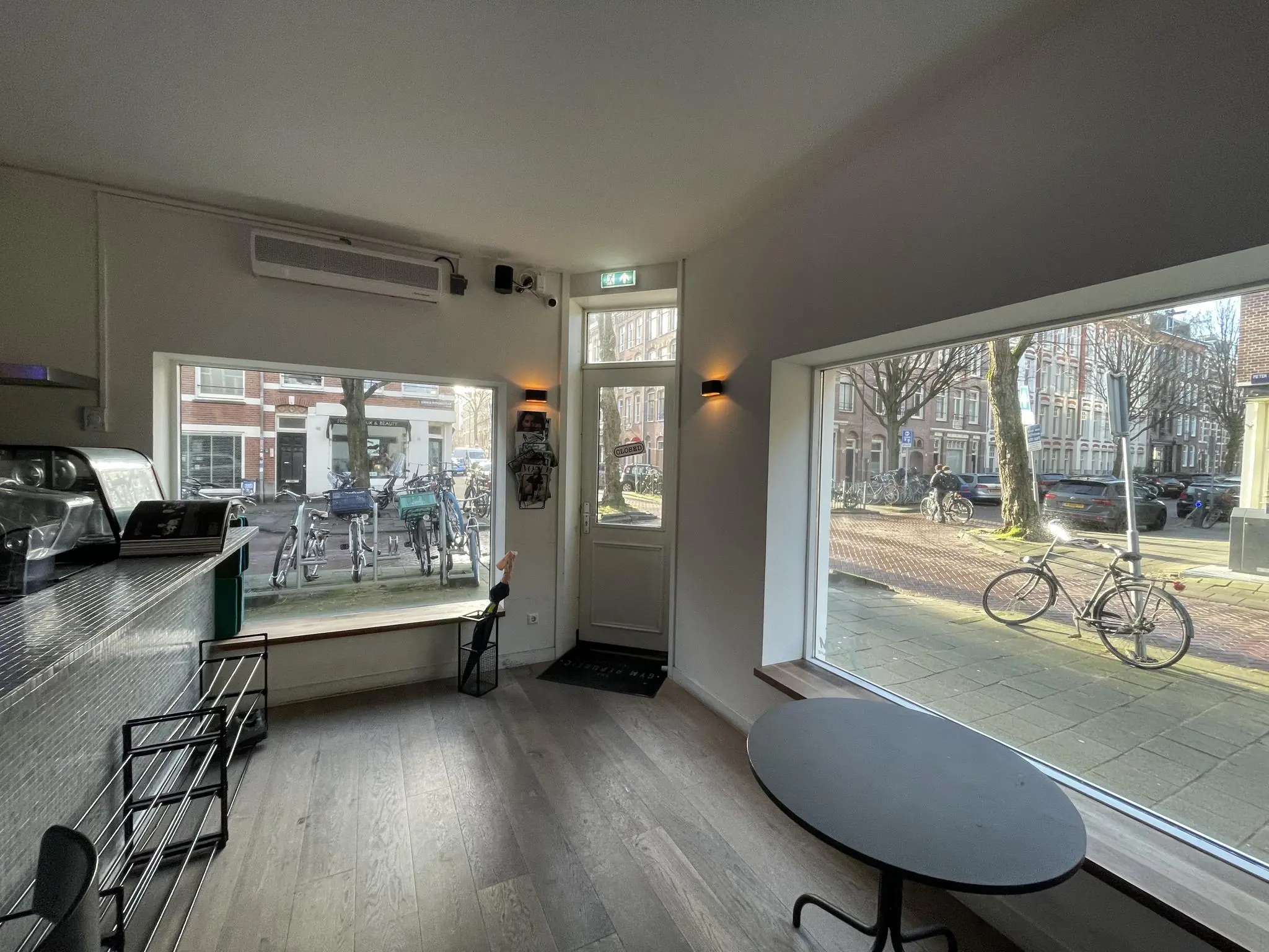 Interieur van een modern café aan de Pieter Baststraat met uitzicht op geparkeerde fietsen en een rustige straat door grote ramen.