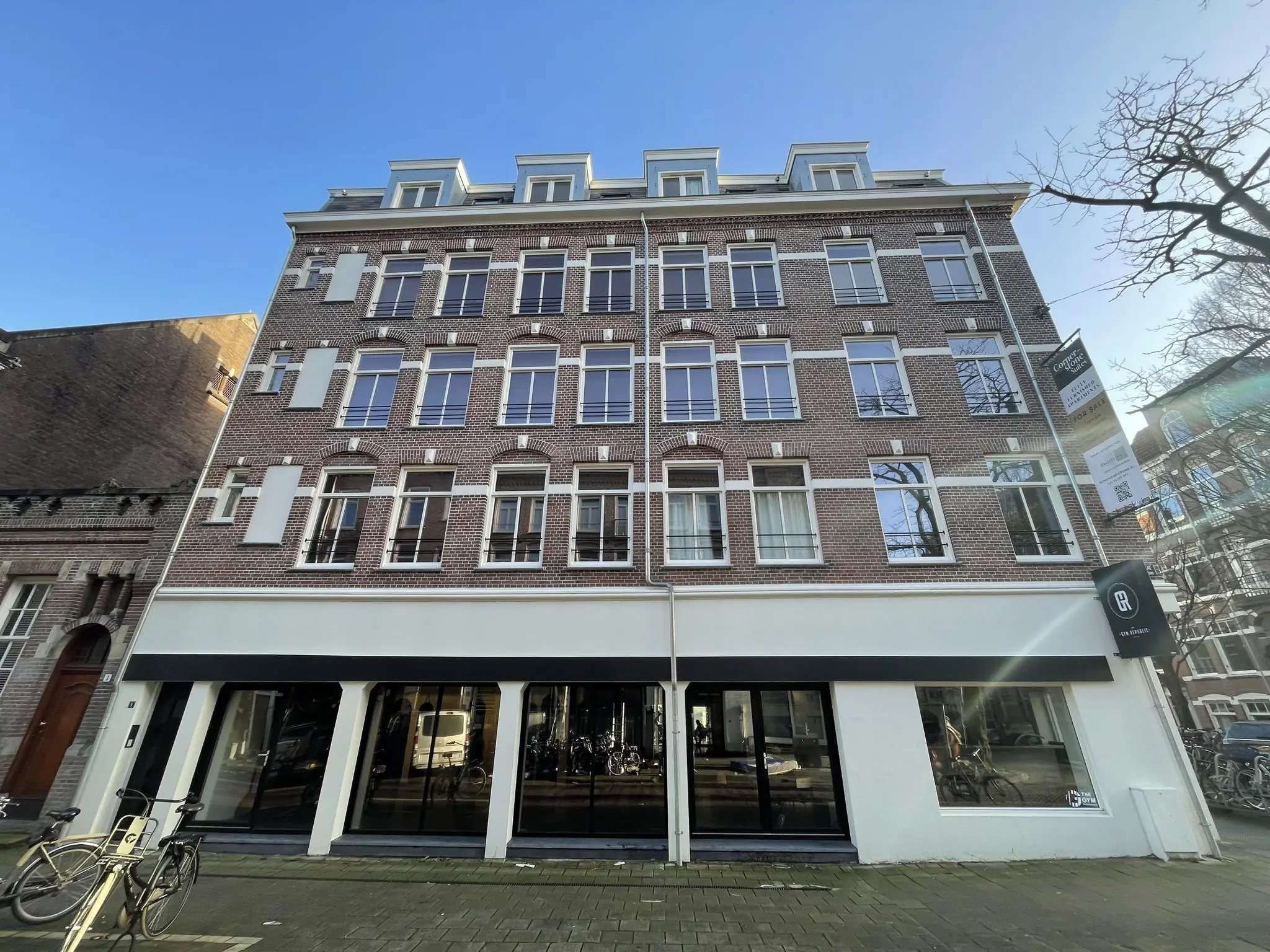 Voorgevel van een klassiek bakstenen pand aan de Pieter Baststraat met grote ramen en een commerciële ruimte op de begane grond.