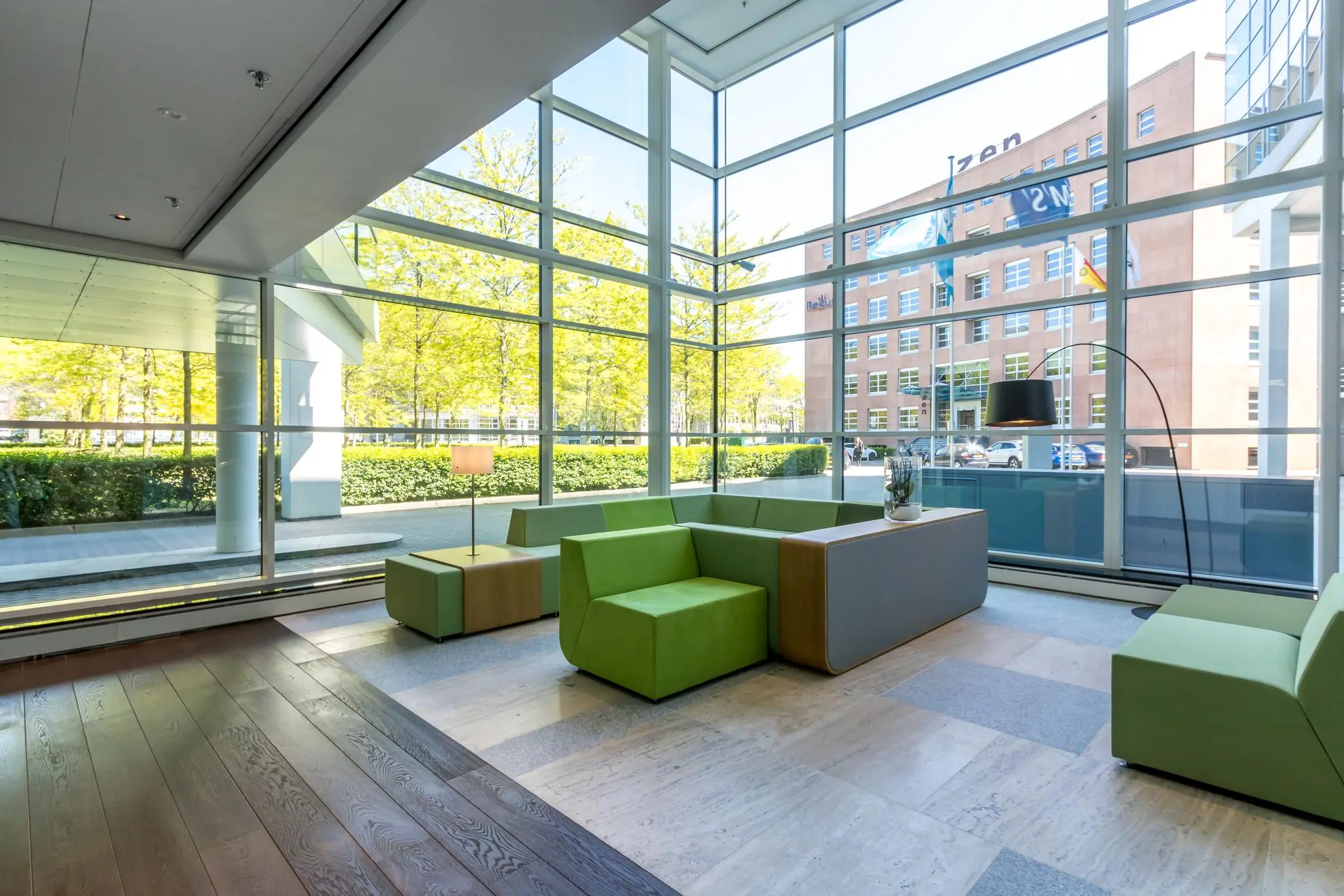Moderne wachtruimte met groen meubilair en grote glazen ramen aan de Newtonlaan.