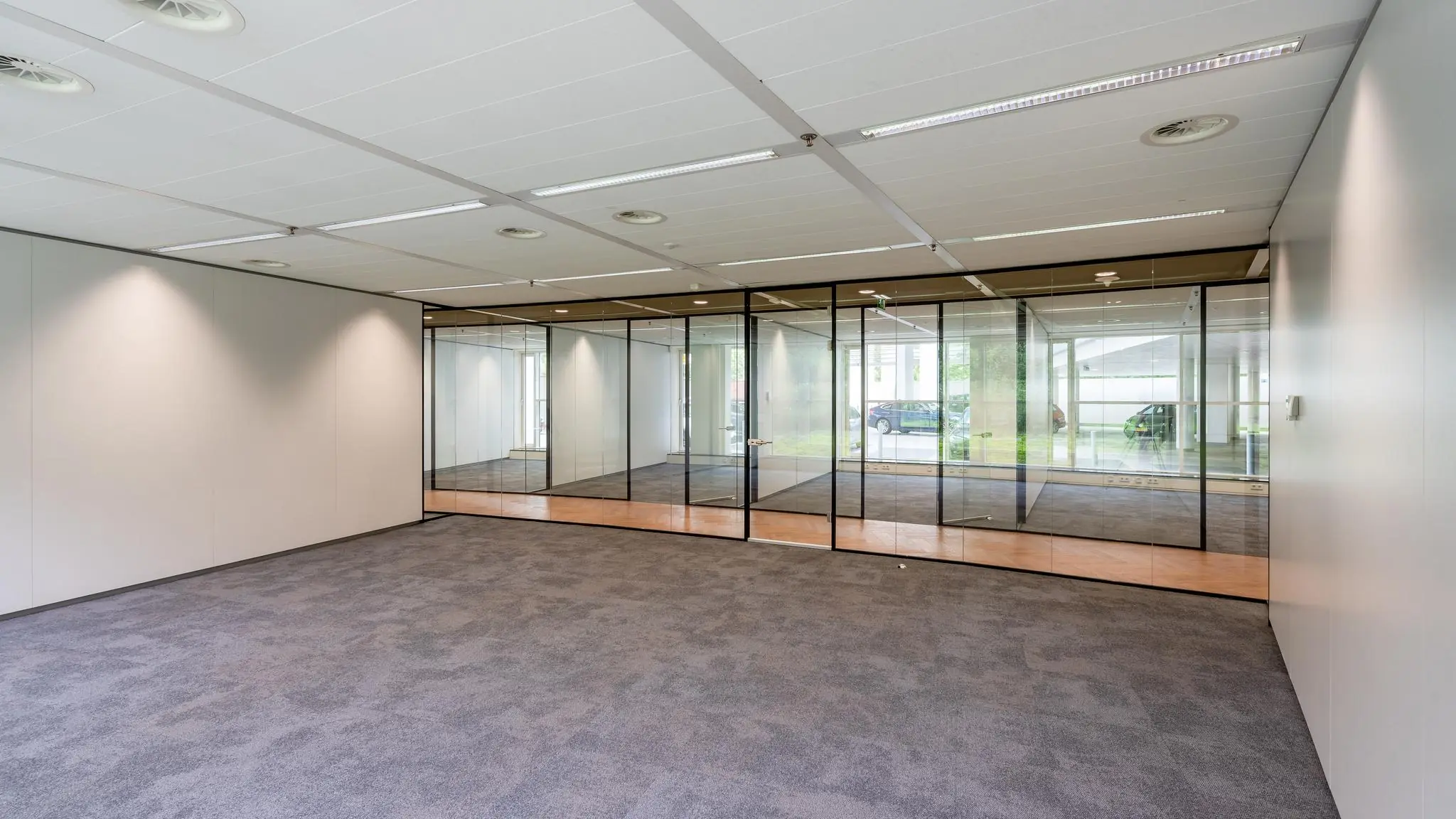 Leeg modern kantoor met vloerbedekking en glazen scheidingswanden aan de Newtonlaan.