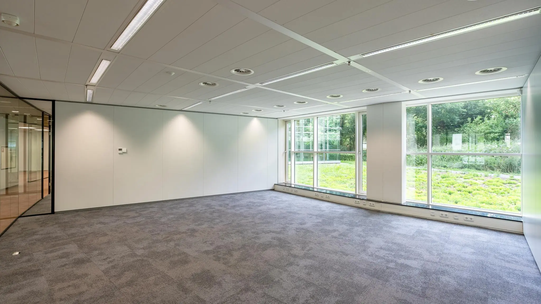 Licht en modern leeg kantoor op Newtonlaan met grote ramen en uitzicht op groen.