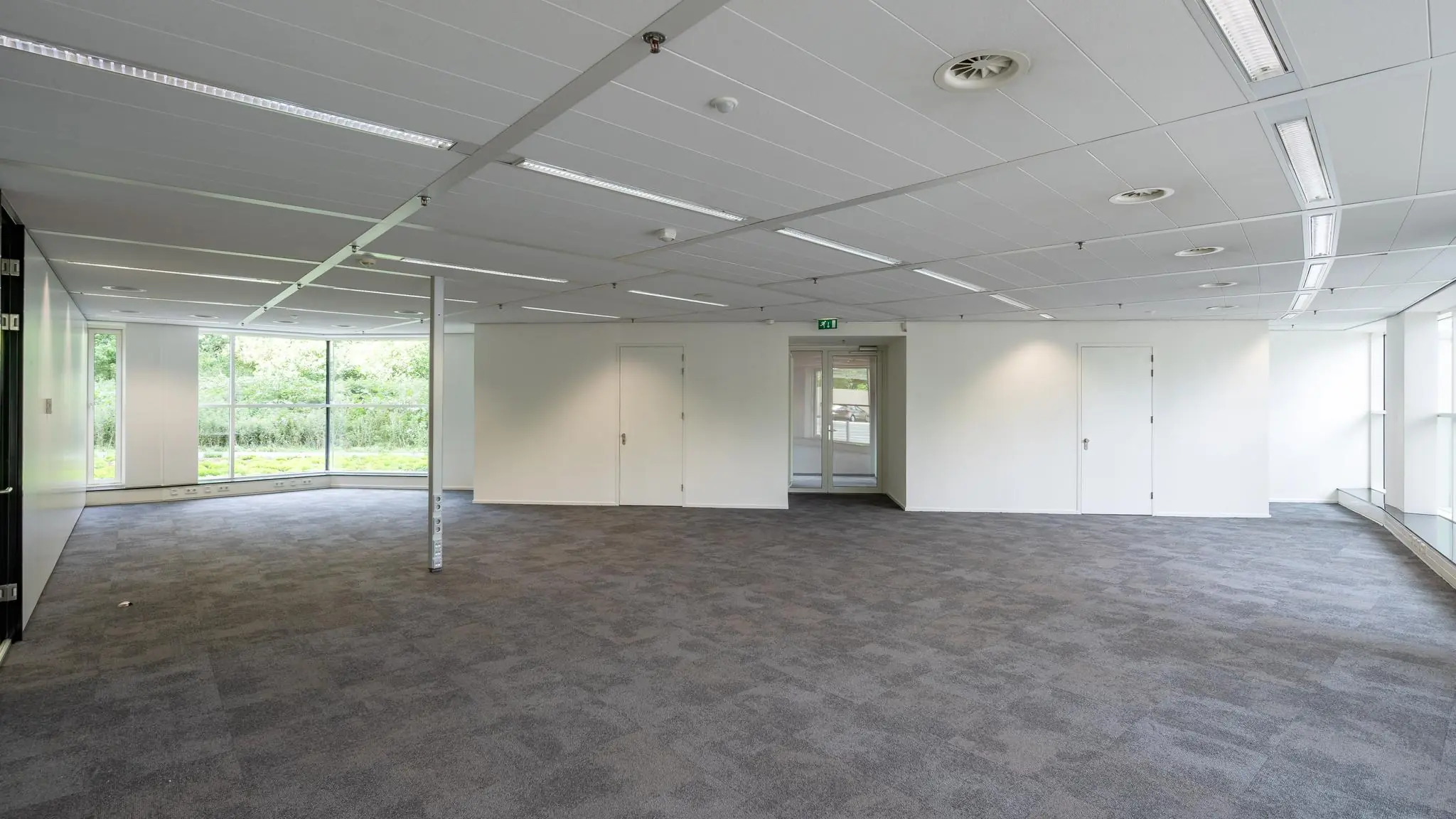 Licht en modern leeg kantoorpand aan de Newtonlaan met grote ramen en grijze vloerbedekking.
