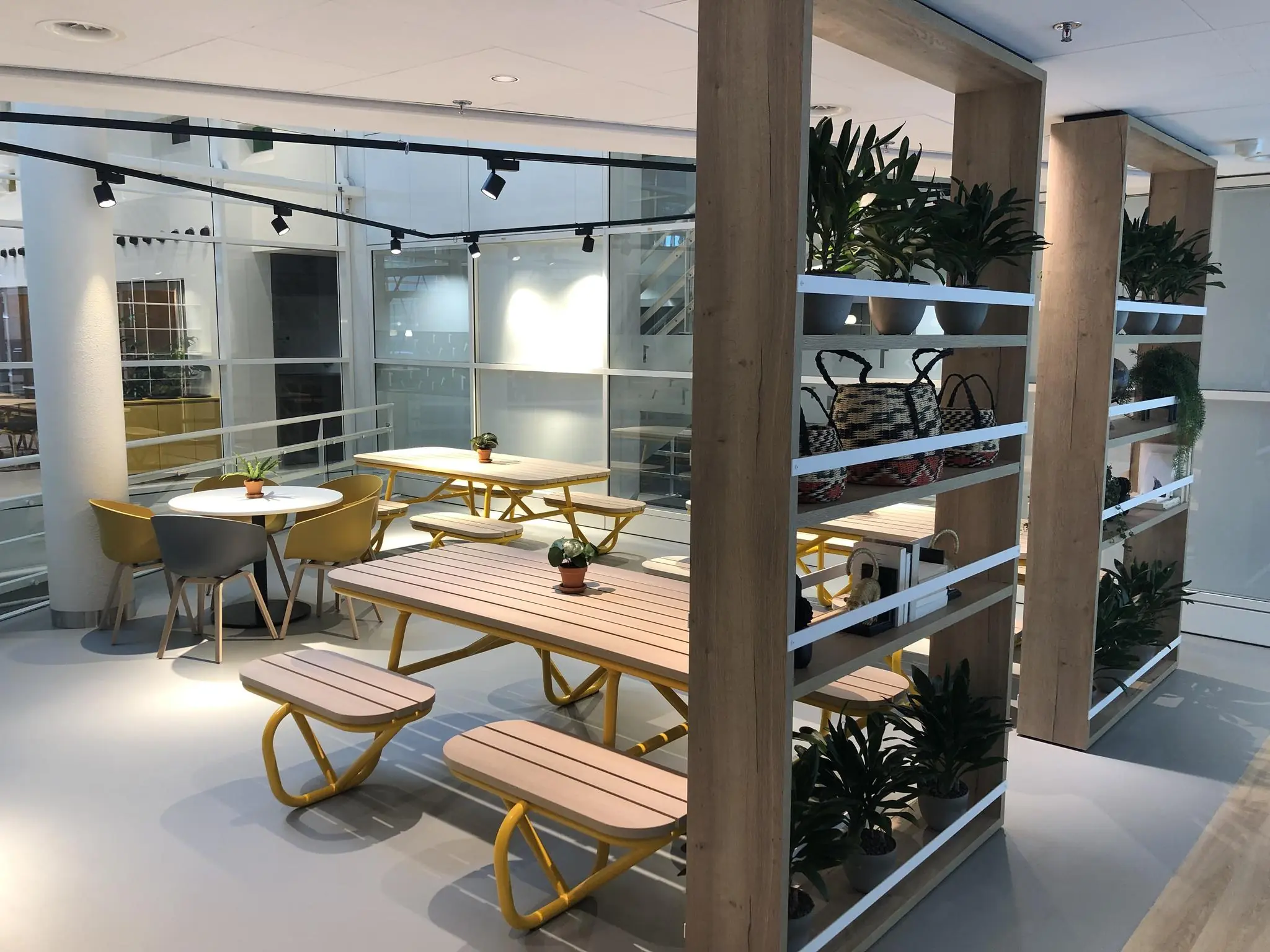 Moderne, open kantoorruimte aan de Newtonlaan met zitjes, houten tafels, planten en decoratieve rekken.