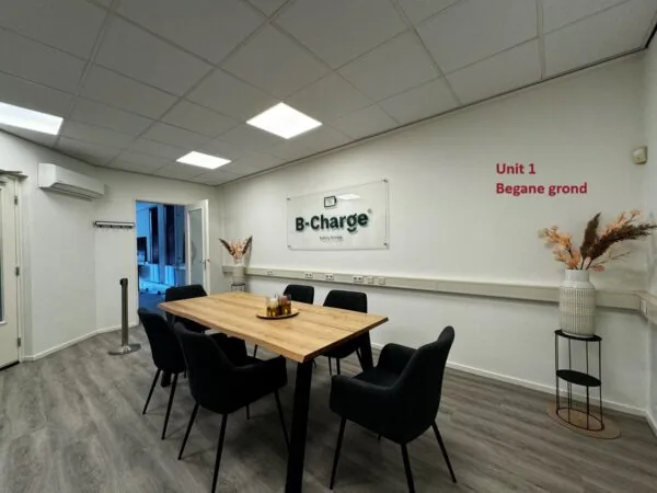 Vergaderruimte van B-Charge op de begane grond van Unit 1 met een houten tafel, zwarte stoelen en decoratieve elementen.