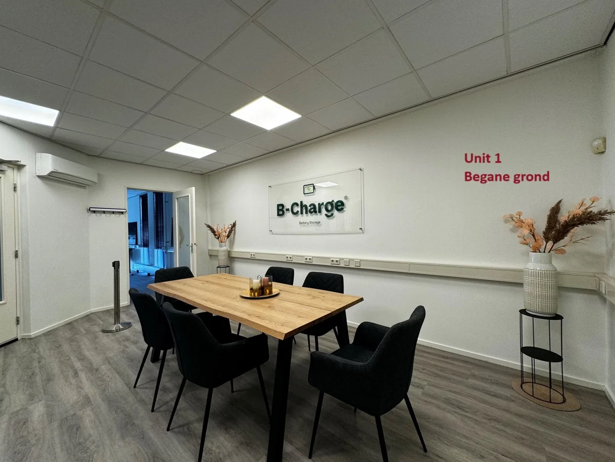 Vergaderruimte van B-Charge op de begane grond van Unit 1 met een houten tafel, zwarte stoelen en decoratieve elementen.