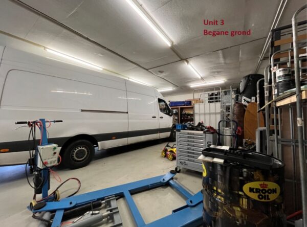 Witte bestelbus in een werkplaats met gereedschap, olie en onderdelen, gemarkeerd als "Unit 3 Begane grond".