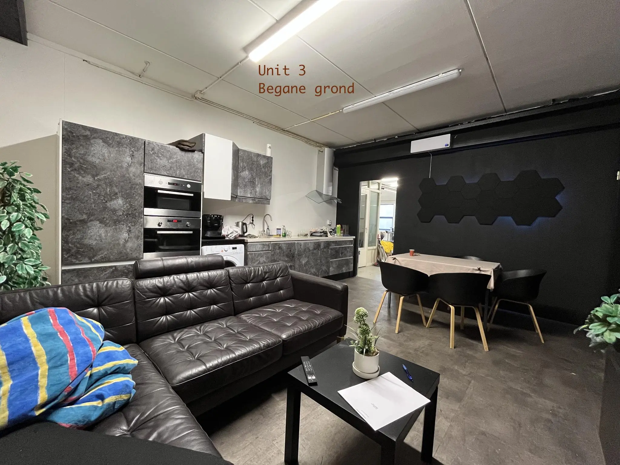 Gemeubileerde woonkamer en keuken van Unit 3 op de begane grond van Bergveste, met een zwarte bank, eettafel en moderne keuken.