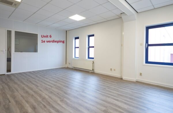 Lichte kantoorruimte met laminaatvloer en raamkozijnen, aangeduid als "Unit 6 1e verdieping".