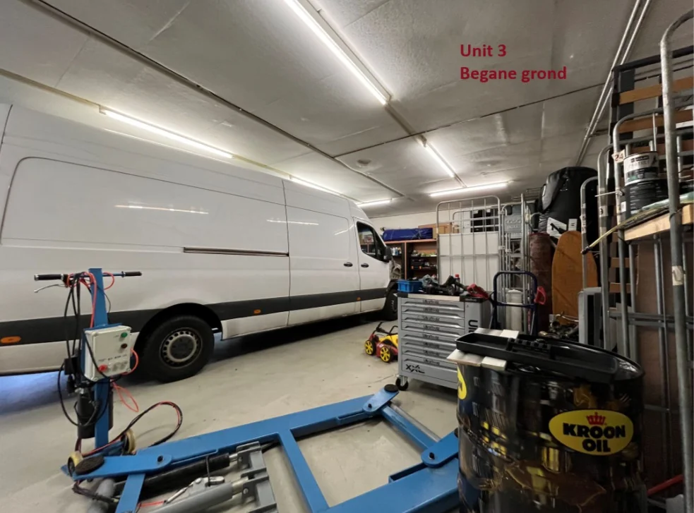 Werkplaats op de begane grond van Unit 3 met een witte bestelbus, gereedschapskist en diverse apparatuur.