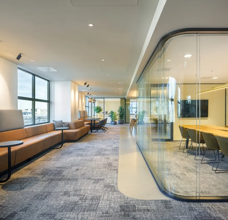 Moderne kantoorruimte aan het Weena met een open loungegedeelte, glazen vergaderruimte en veel natuurlijk licht.