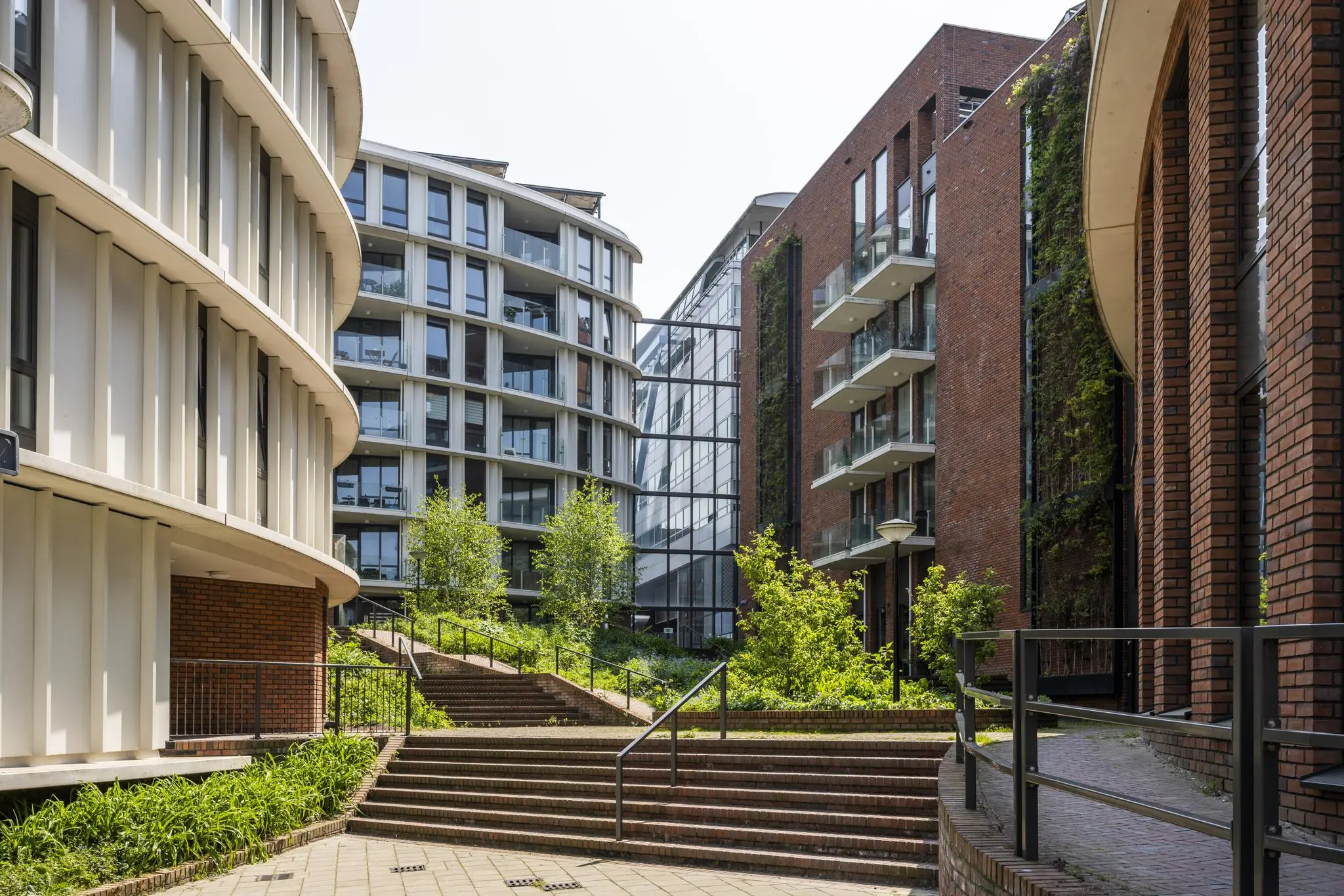 Moderne appartementencomplexen met veel glas en baksteen rond een groen plein op het Bos en Lommerplein in Amsterdam.