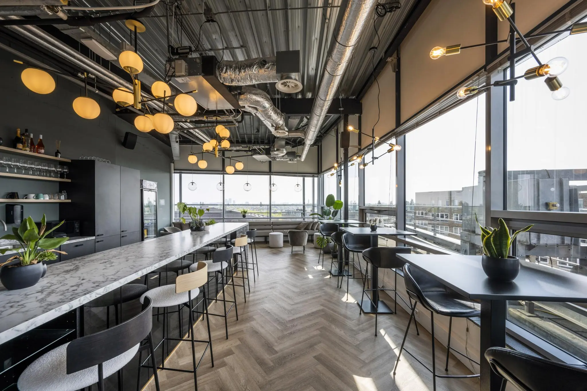Modern ingerichte kantoorruimte aan het Bos en Lommerplein met hoge ramen, marmeren bar en industriële verlichting.