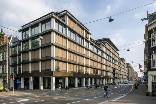 Modern kantoorgebouw aan de Vijzelstraat in Amsterdam, met fietsers en voetgangers op straat.