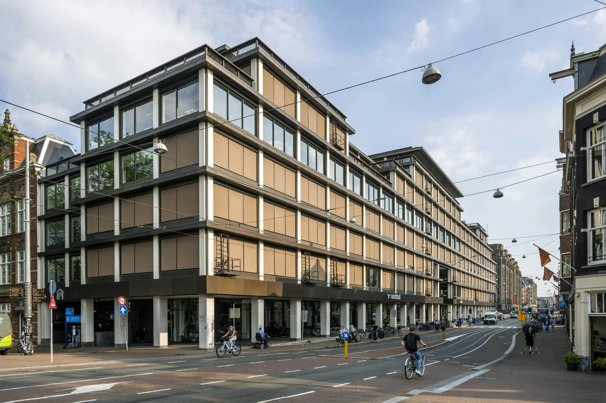 Modern kantoorgebouw aan de Vijzelstraat in Amsterdam, met fietsers en voetgangers op straat.