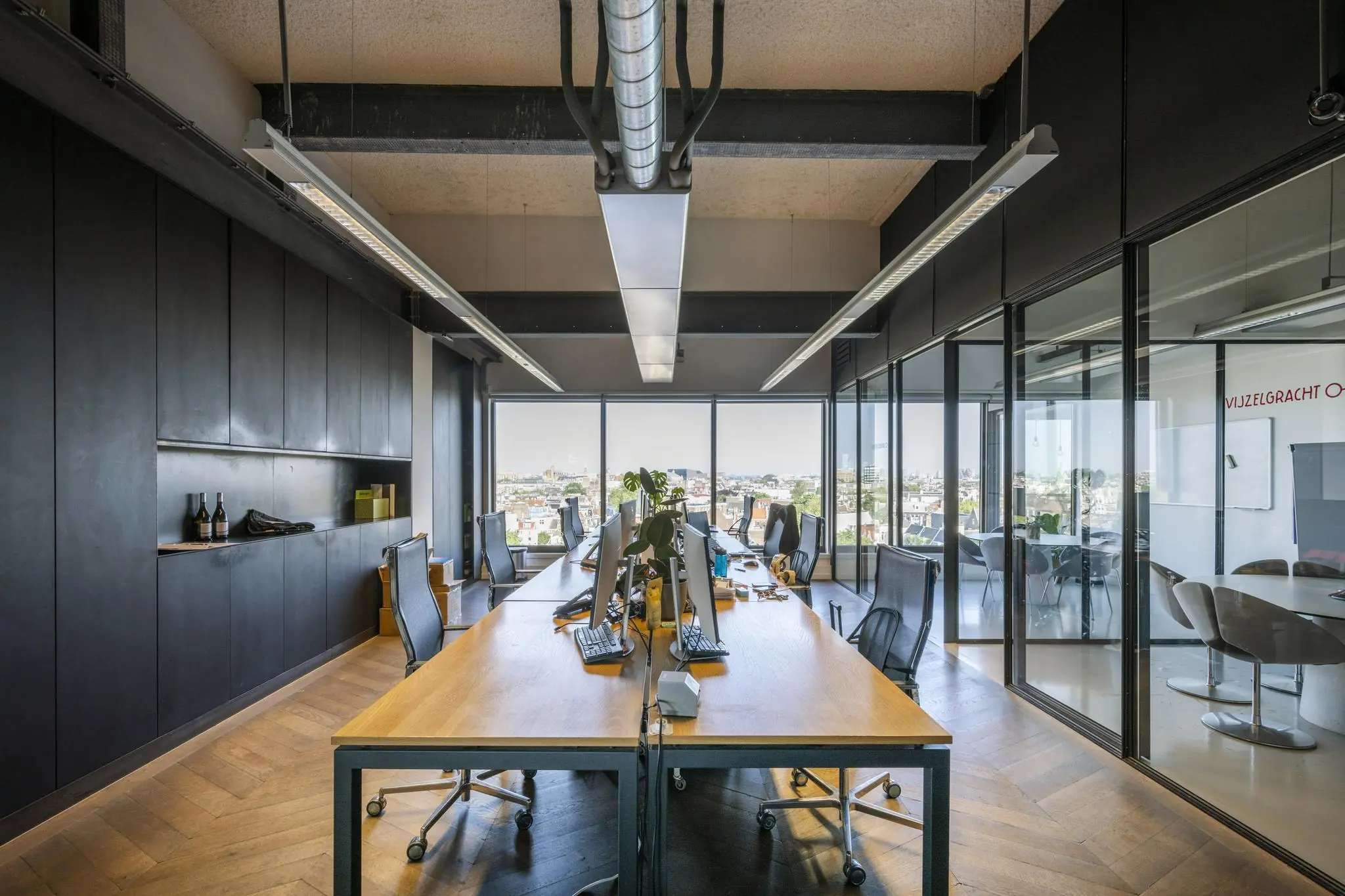 Modern kantoorinterieur aan de Vijzelstraat met open werkplekken, glazen vergaderruimtes en uitzicht over de stad.