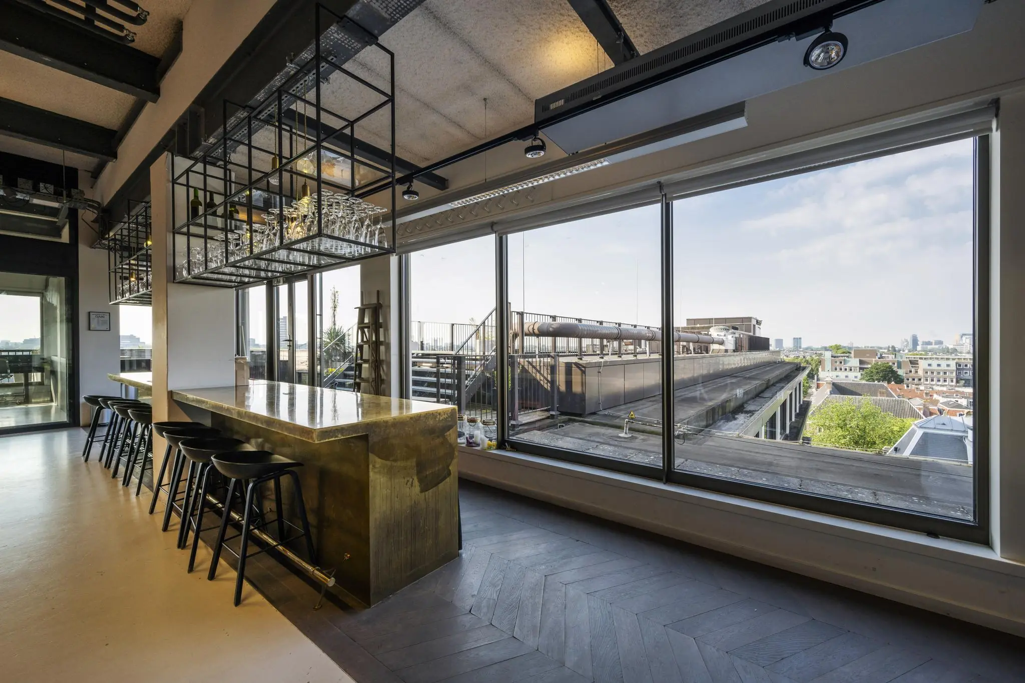Moderne barruimte met gouden bartafel en uitzicht op dakterras aan de Vijzelstraat in Amsterdam.