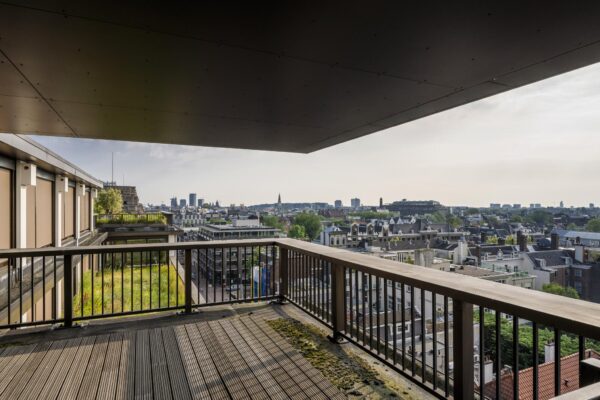 Uitzicht vanaf een balkon aan de Vijzelstraat met uitzicht over de daken van Amsterdam en de skyline in de verte.