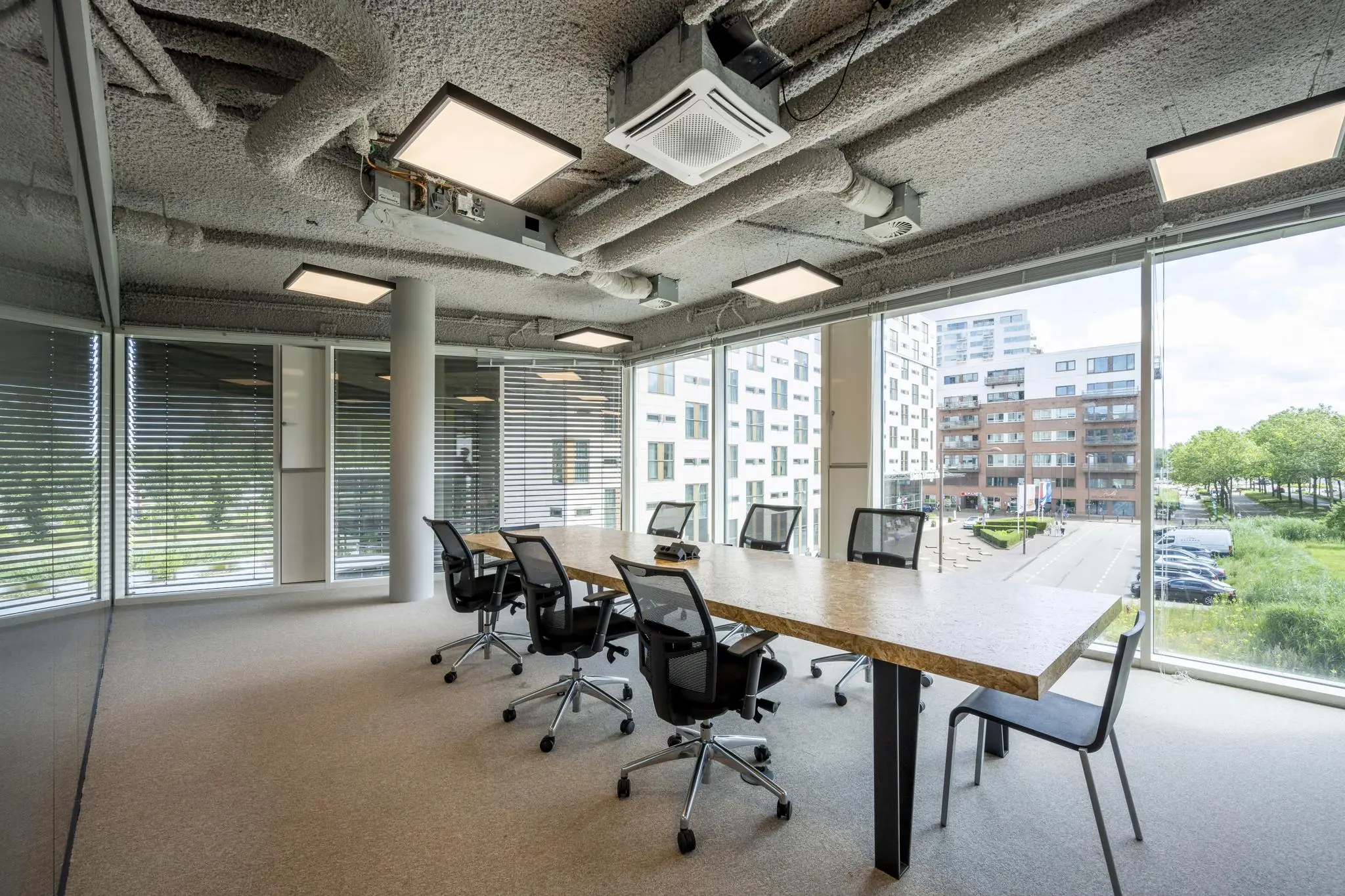 Vergaderruimte met modern interieur en uitzicht op gebouwen aan het John M. Keynesplein.