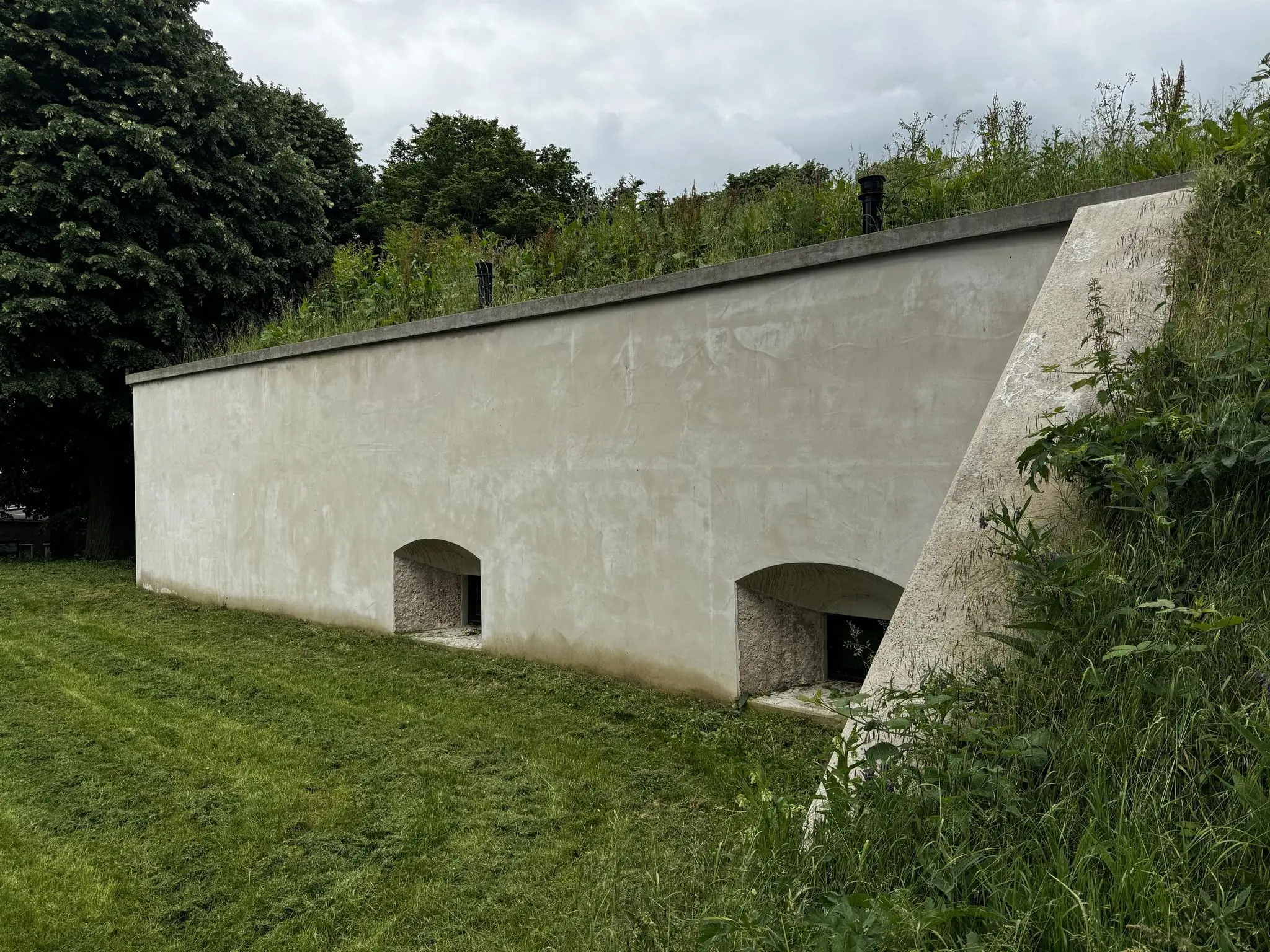 Betonnen kazemat aan de Lekdijk met begroeid dak en twee schietgaten aan de voorkant.