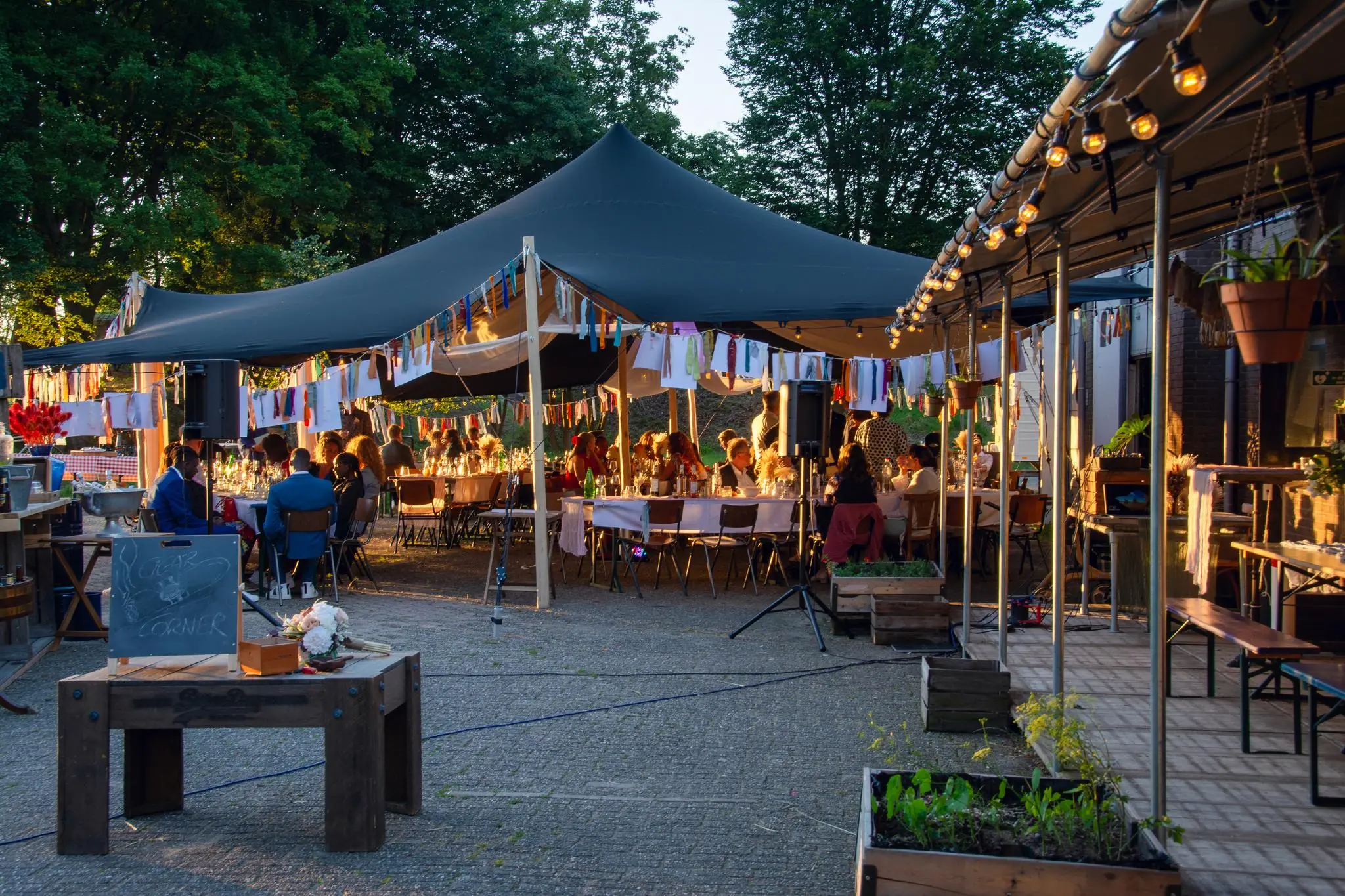 Sfeervol diner onder een grote stretchtent met feestverlichting en kleurrijke slingers aan de Lekdijk.
