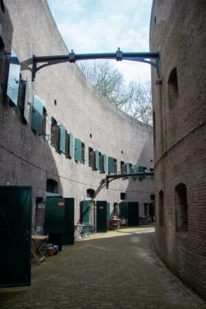 Binnenplein van historisch fort aan de Lekdijk met bakstenen muren en donkergroene deuren.