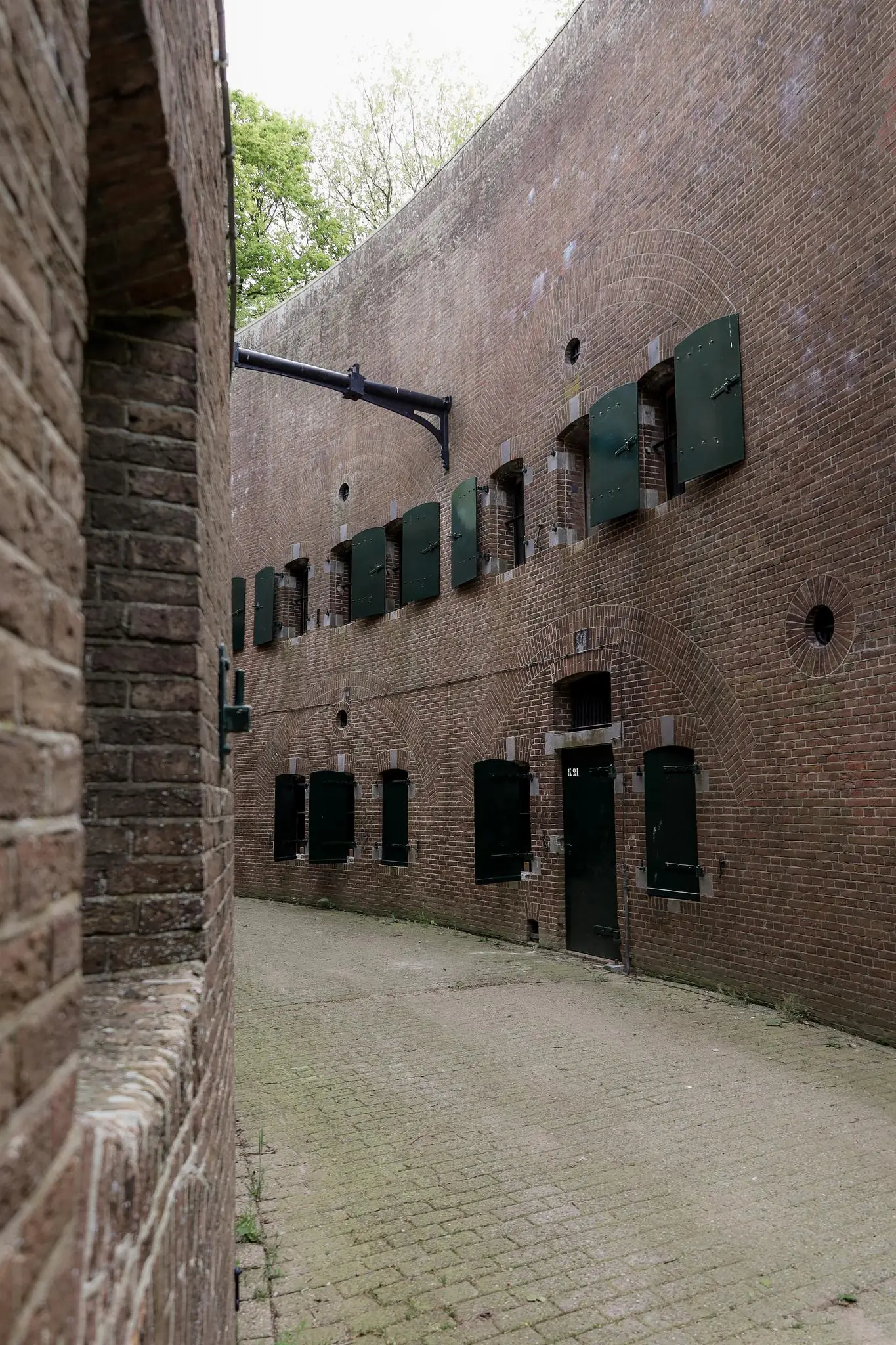 Binnenplaats van een oud fort aan de Lekdijk met hoge bakstenen muren en gesloten groene luiken.