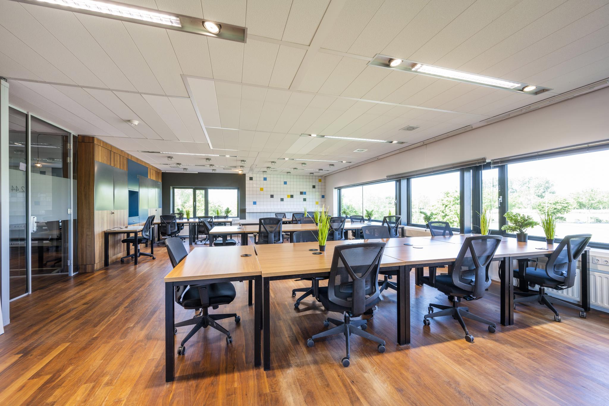 Moderne en lichte kantooruimte aan de Prof. W.H. Keesomlaan met open werkplekken, ergonomische stoelen en grote ramen met uitzicht op groen.