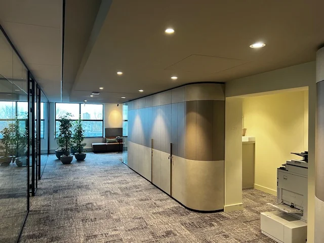 Moderne kantoorruimte aan het Weena met glazen wanden, planten en een zithoek bij het raam.