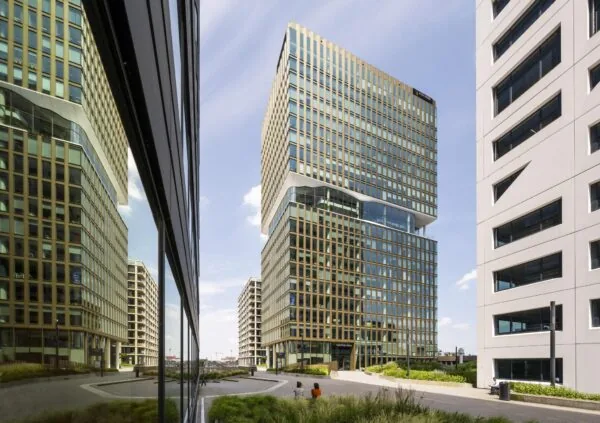 Modern kantoorgebouw op het Stadsplateau met goudkleurige gevel en glazen ramen, geflankeerd door andere hoge gebouwen.