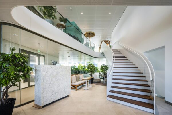 Moderne en lichte kantoorruimte met een brede houten trap, glazen wanden en veel groene planten op het Stadsplateau.