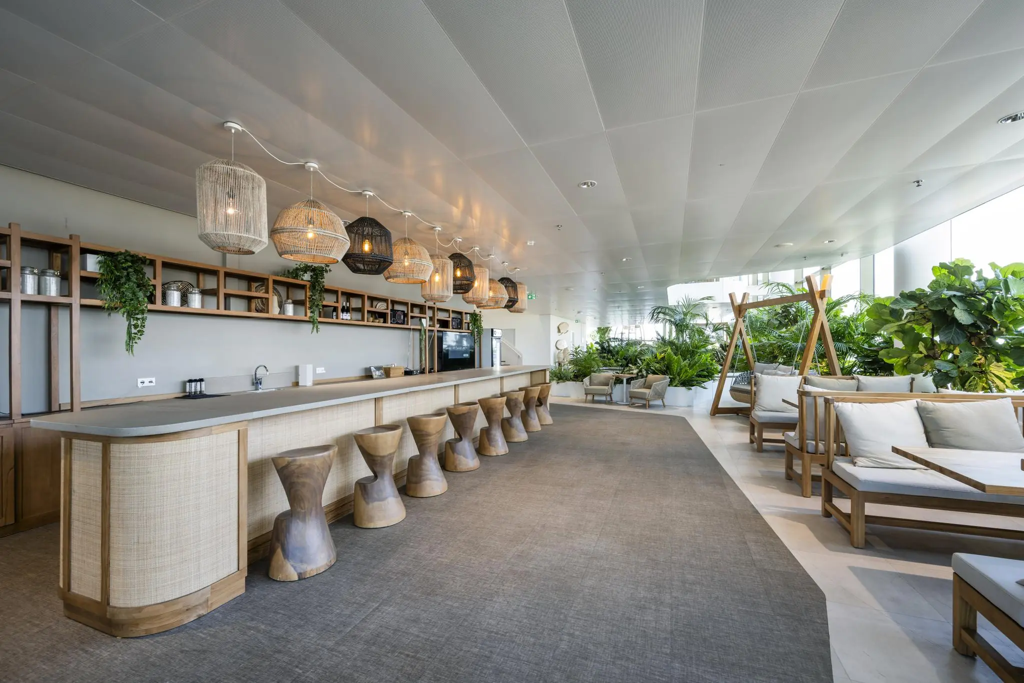 Modern ingerichte lounge met een houten bar, designkrukken en veel groen op het Stadsplateau.