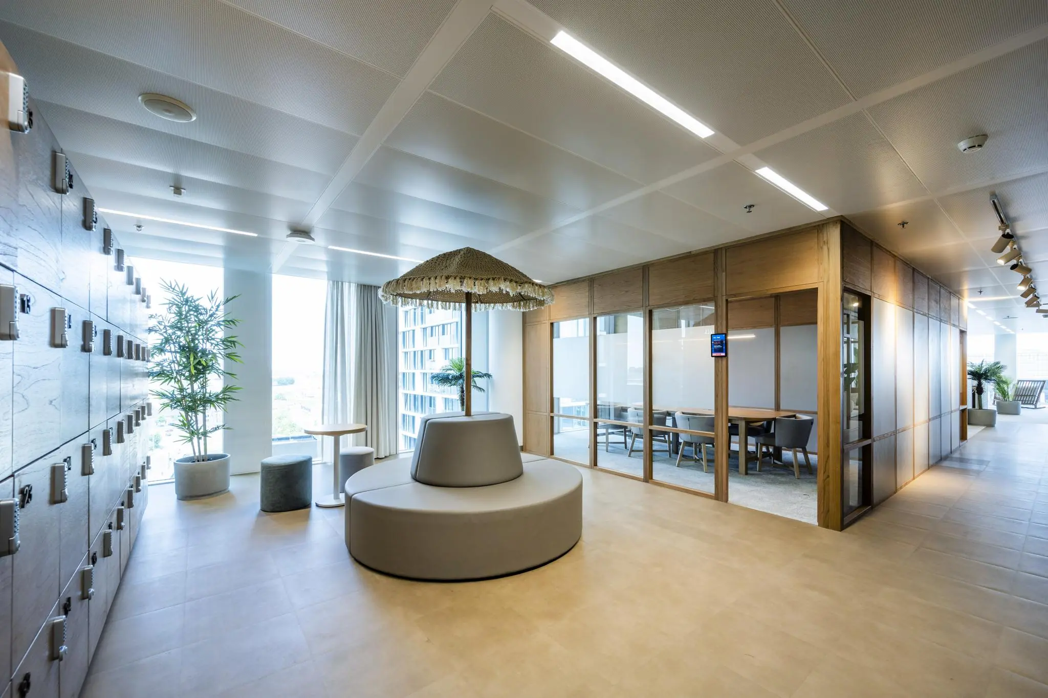 Moderne kantoorruimte op het Stadsplateau met lockers, ronde zitbank met parasol, vergaderruimte en grote ramen met veel daglicht.