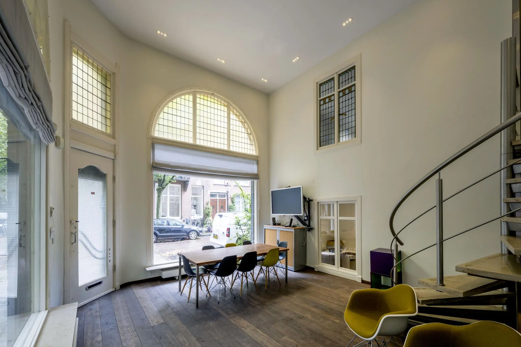 Moderne vergaderruimte aan de Lomanstraat met hoge plafonds, grote ramen, een lange tafel en een wenteltrap.