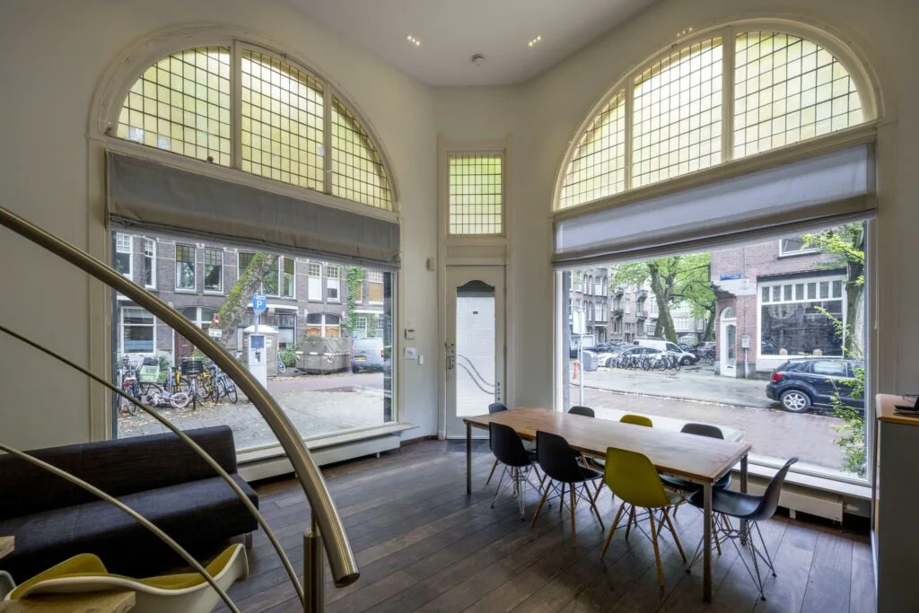 Interieur van een modern woonhuis aan de Lomanstraat met grote ramen, hoge plafonds en uitzicht op een Amsterdamse straat.