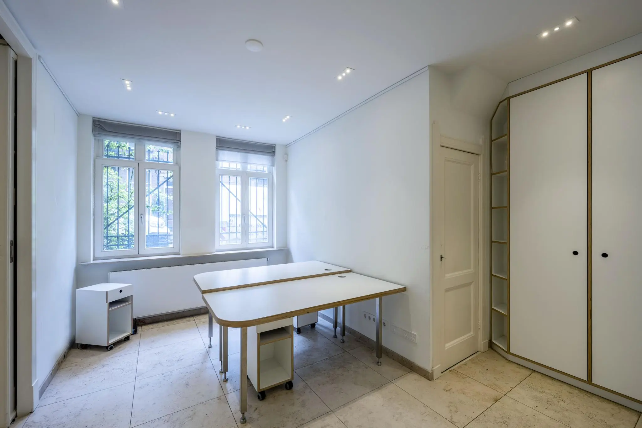 Lichte kantoorruimte aan de Lomanstraat met twee bureaus, grote ramen en ingebouwde kastruimte.