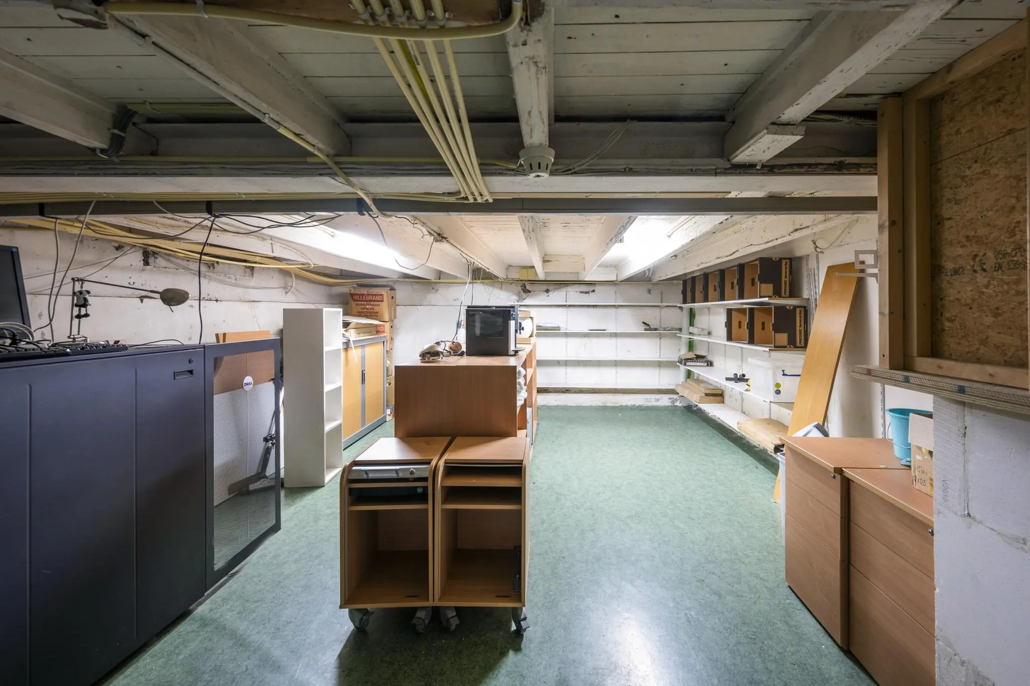 Kelderruimte aan de Lomanstraat met lage plafonds, opbergkasten, archiefdozen en losse meubelstukken.