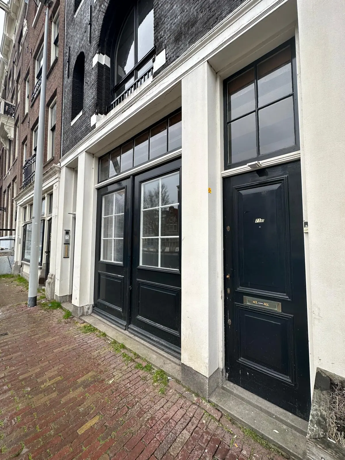 Voorgevel van een gebouw aan de Herengracht met zwarte deuren en witte kozijnen.