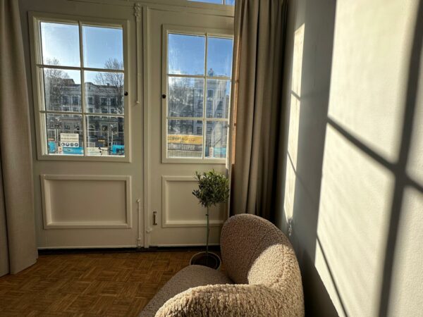 Zonnige zitkamer aan de Herengracht met uitzicht op klassieke gevels en een bouwplaats.