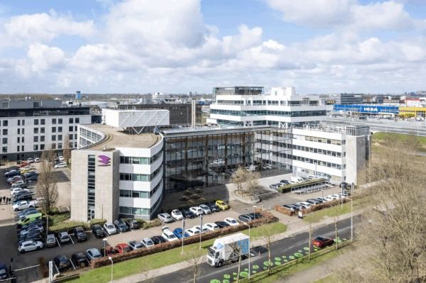 Kantoorgebouw aan de Paalbergweg in Amsterdam met parkeergelegenheid en herkenbaar logo op de gevel.