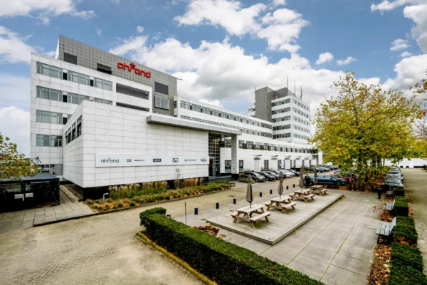 Een modern kantoorgebouw van Ahrend met parkeerplaatsen en een picknickplaats aan de voorzijde.