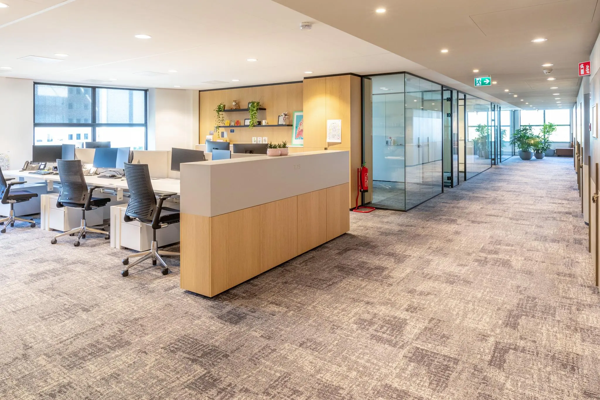 Modern kantoorinterieur op Weena met open werkplekken, glazen vergaderruimtes en een lichte, ruimtelijke gang.