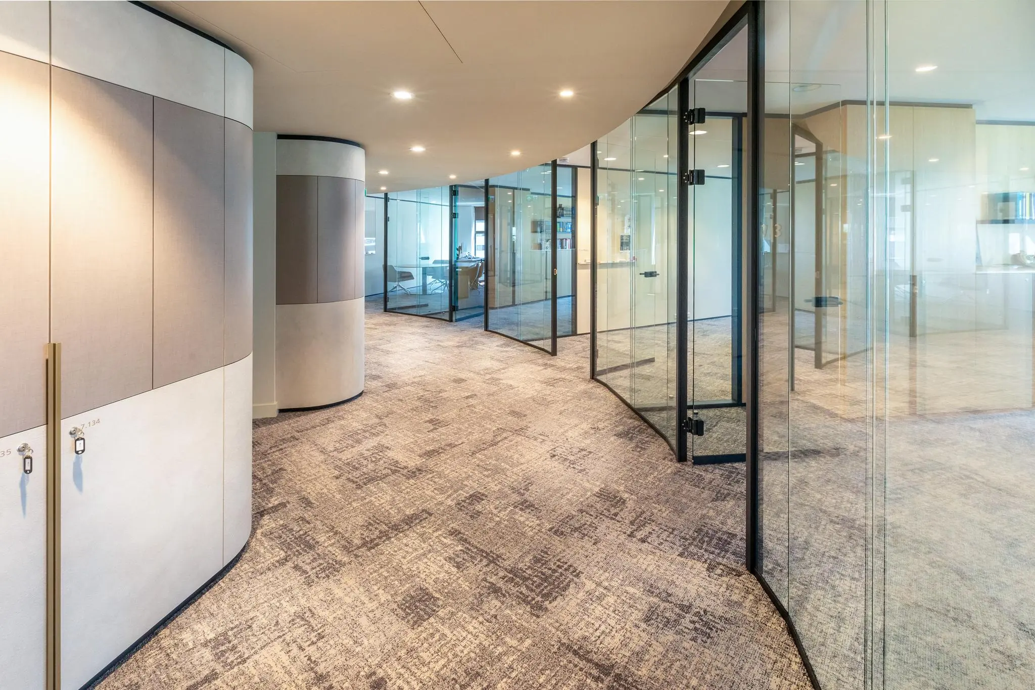 Moderne kantoorruimte aan het Weena met gebogen glazen wanden en zachte vloerbedekking.