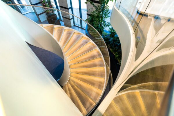 Moderne houten wenteltrap met glazen balustrade in het kantoorgebouw aan het Weena.
