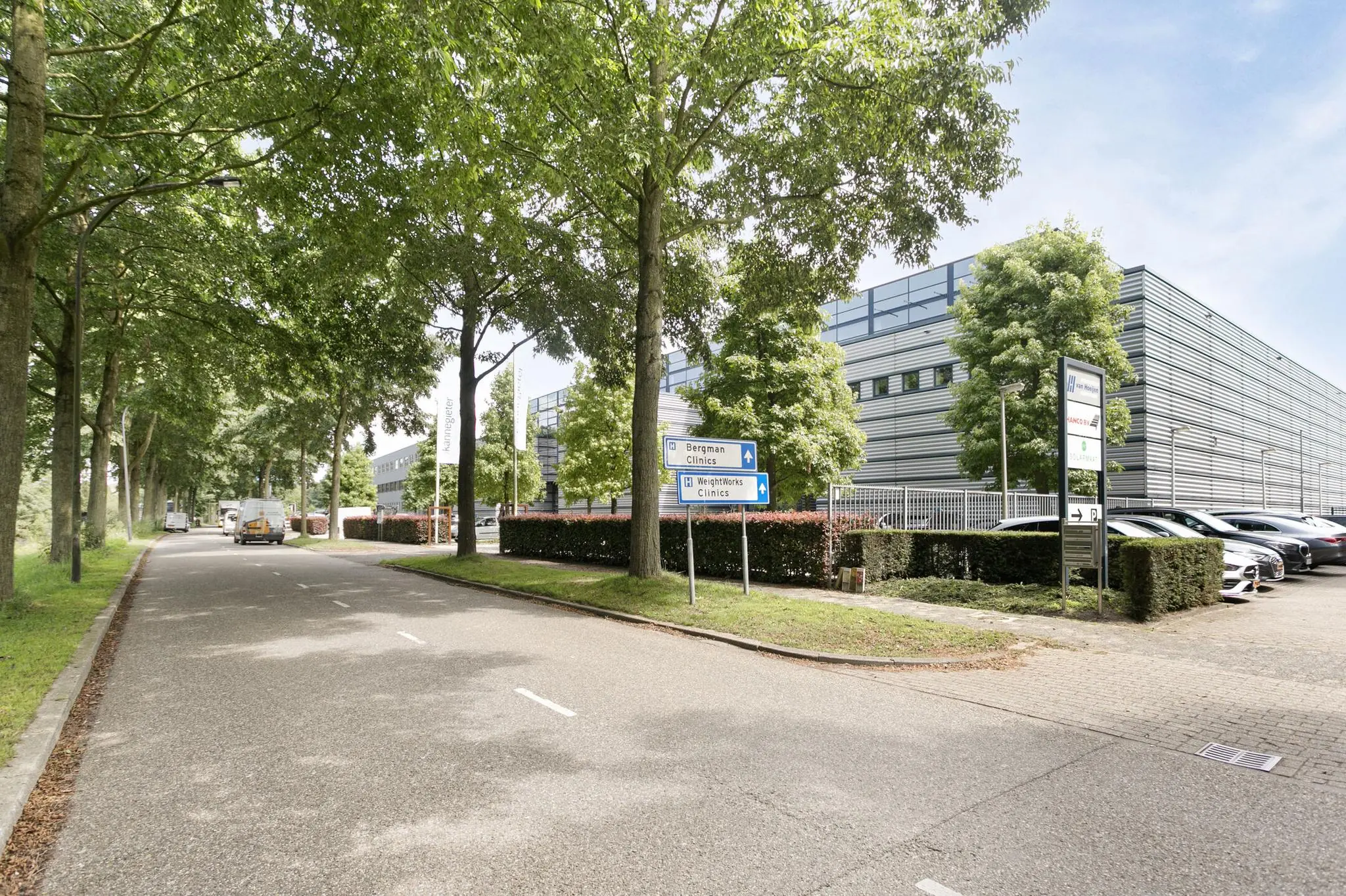 Bedrijventerrein met kantoren en parkeerplaatsen langs een boomrijke straat in de buurt van Bergman Clinics en WeightWorks Clinics.