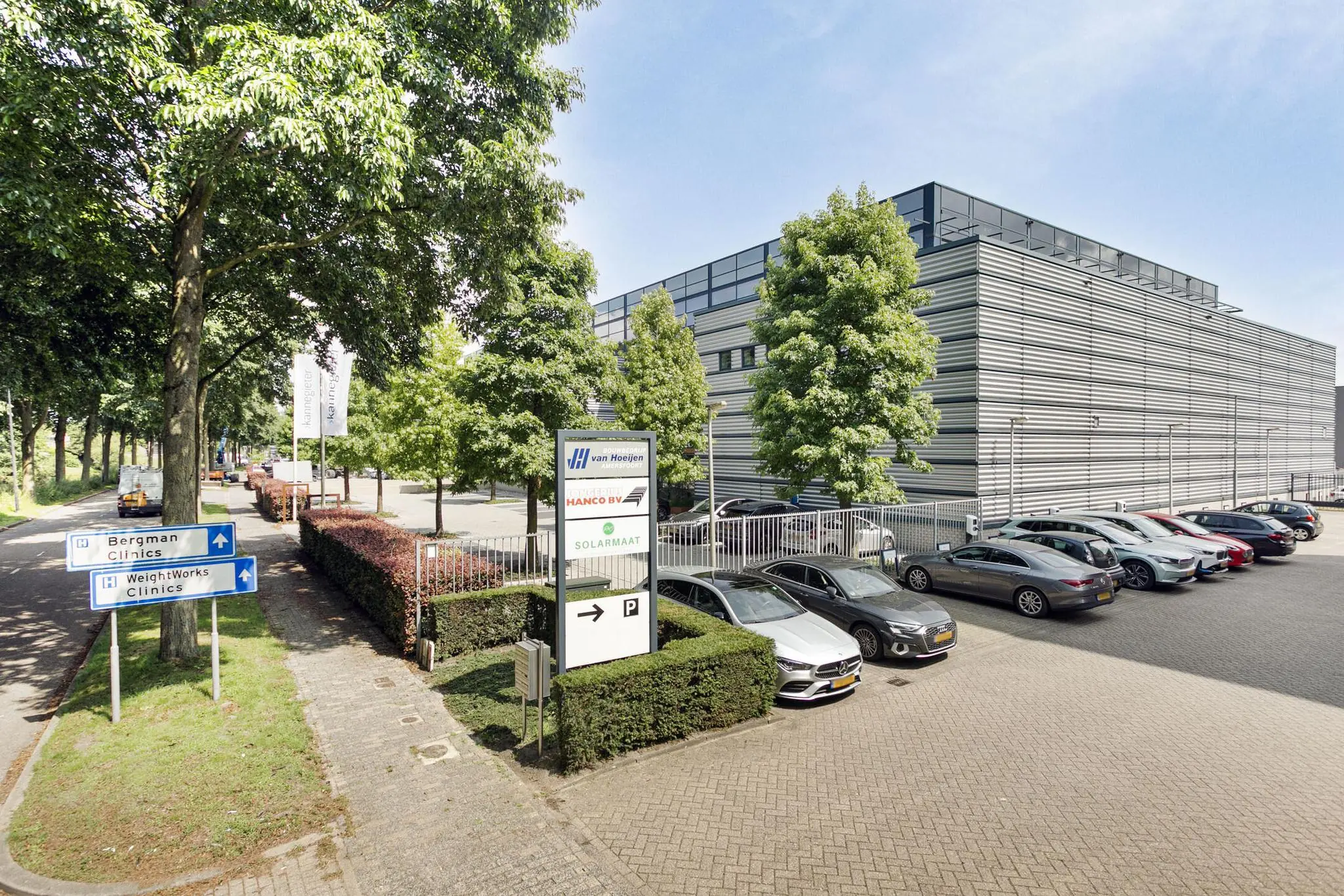 Moderne bedrijfsgebouwen met parkeerterrein en bewegwijzering naar omliggende klinieken.